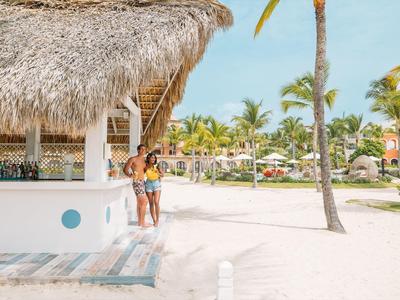 Twee vrouwen staan onder een palmbladdak bij een strandbar in een tropisch resort.