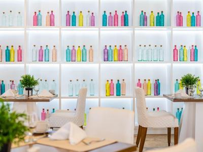 Modern restaurant met kleurrijke waterflessen en witte meubels.