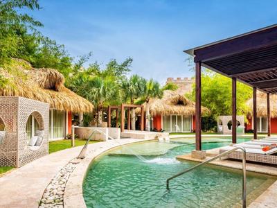 Luxe buitenzwembad met ligstoelen en bungalows in een tropisch resort.