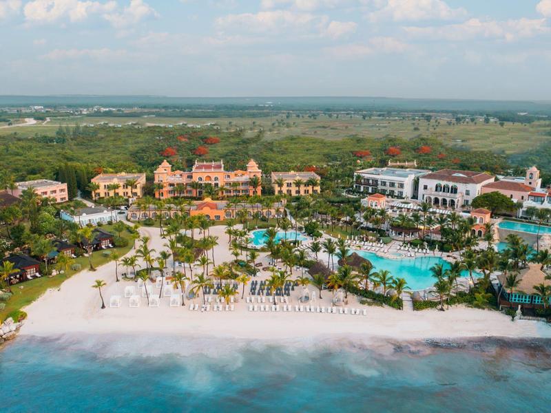 Luxe resort aan het strand met zwembaden en weelderig groen langs de kustlijn.