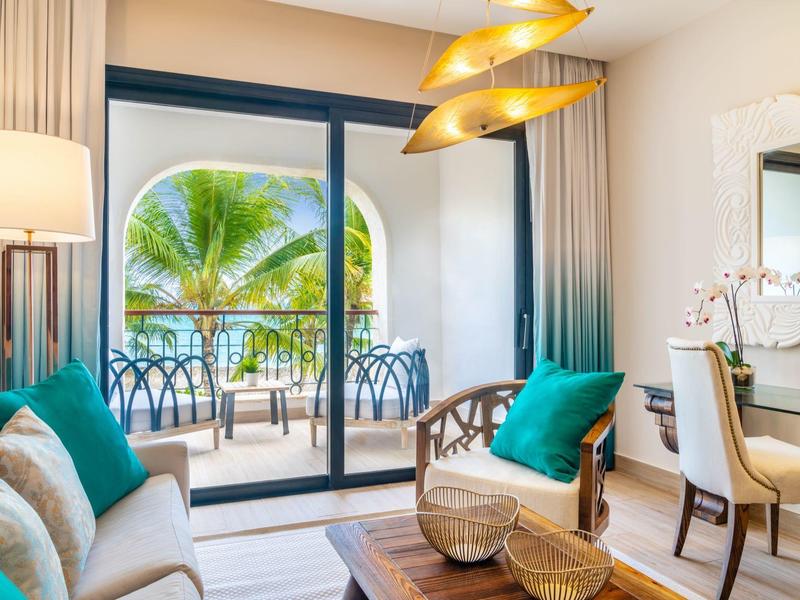 Lichte woonkamer met balkon, tropisch uitzicht en moderne inrichting in groen- en blauwtinten.