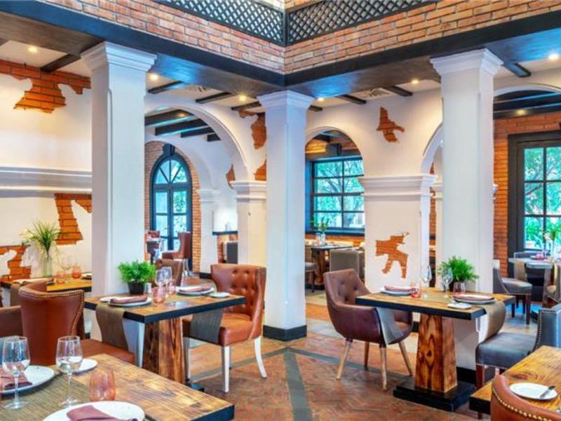 Licht restaurant met ronde zuilen, houten plafonds en elegant gedekte tafels