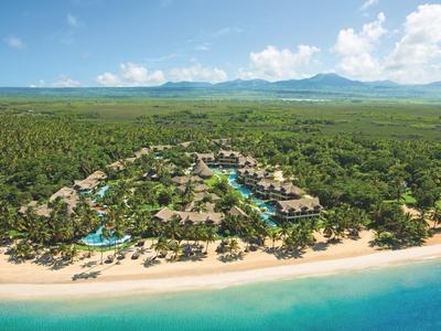 Vogelperspektive eines tropischen Strandresorts mit Pools und üppiger Vegetation.