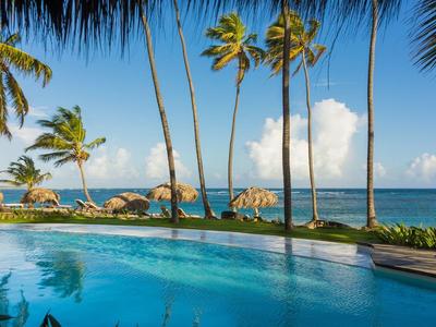 Pool mit Palmen und Meerblick bei klarem Himmel in tropischem Resort