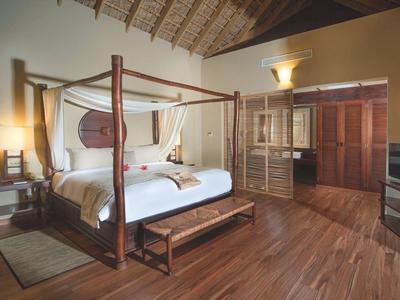 Elegantes Schlafzimmer mit Himmelbett, Holzboden und rustikalem Dekor in warmen Farben.