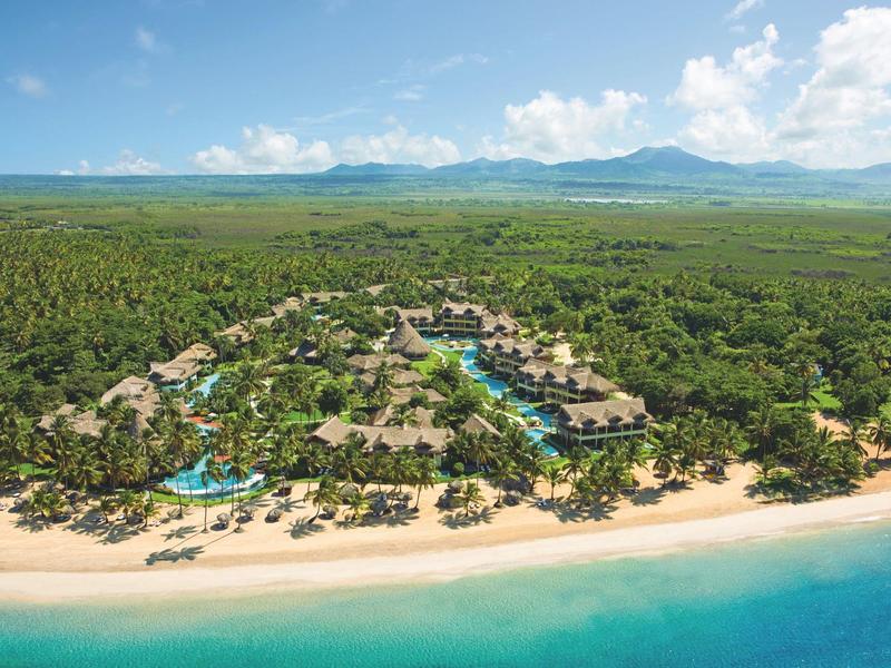 Vogelperspektive eines tropischen Strandresorts mit Pools und üppiger Vegetation.
