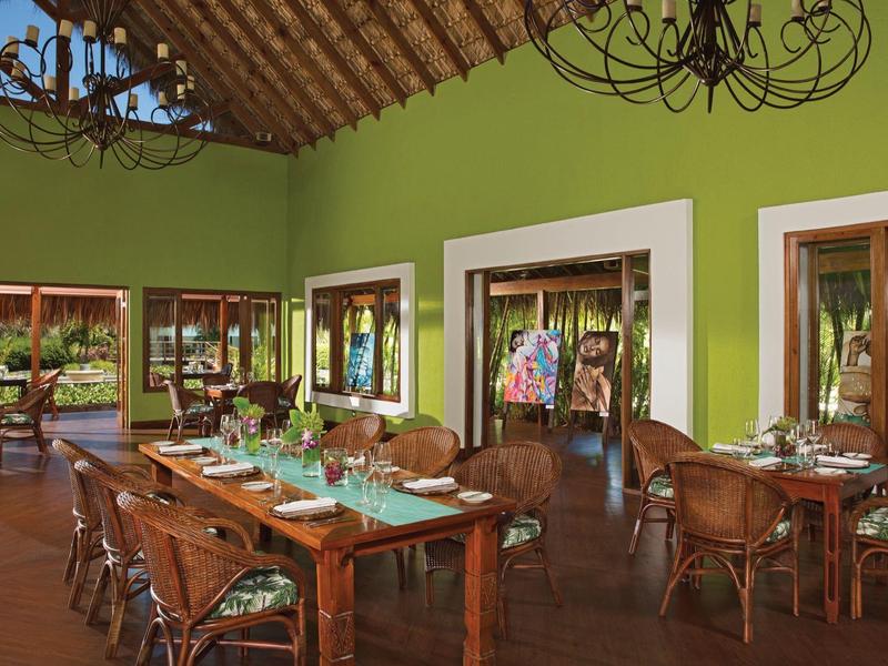 Gemütlicher, grüner Speiseraum mit Holzmöbeln und Blick auf Garten und Schwimmbad.