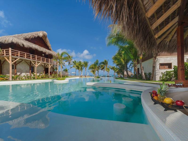 Luxuriöser Hotelpool mit Palmen und Strohdächern unter blauem Himmel