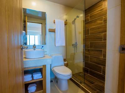 Kleines modernes Badezimmer mit Holzakzenten, Toilette, Waschtisch, Spiegel und Dusche mit Glaswand.