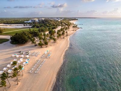 Letecký pohled na klidnou písečnou pláž s lehátky a slunečníky u moře.