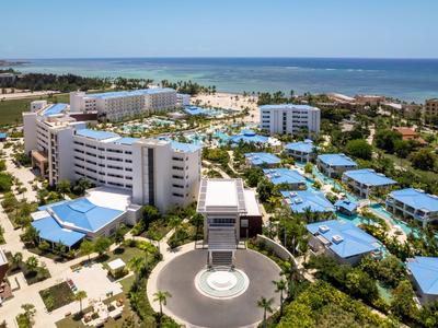 Large hotel resort with multiple buildings and pools right by the sea.