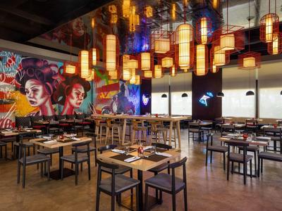 Modern restaurant with colorful mural and hanging lantern lighting.