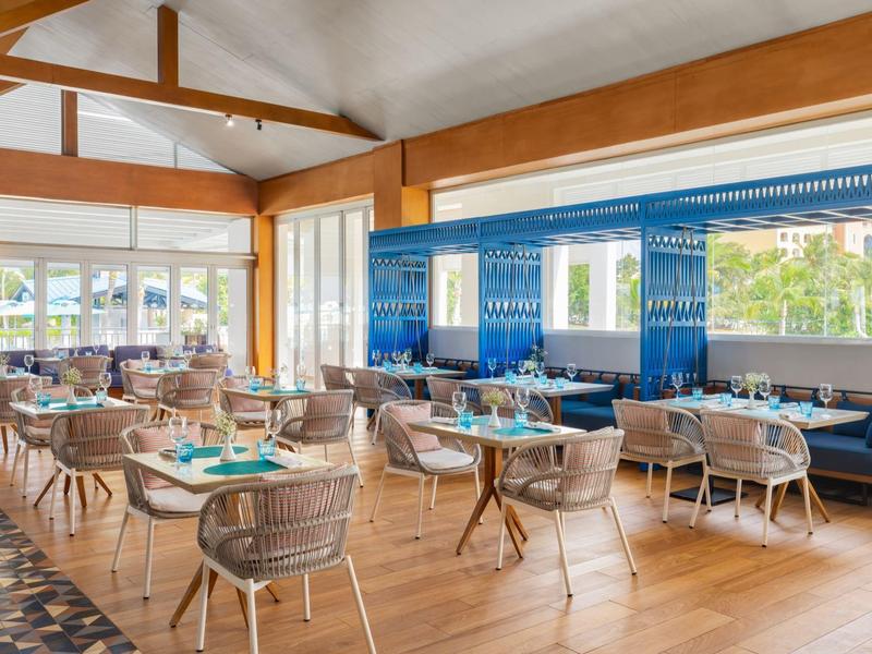 Bright restaurant with wooden floors, modern seating arrangements, and large windows overlooking greenery.