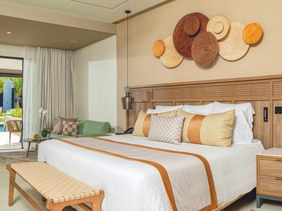 Helles Schlafzimmer mit großem Bett, Holzmöbeln und dekorativen Wandkörben, Zugang zu Terrasse.