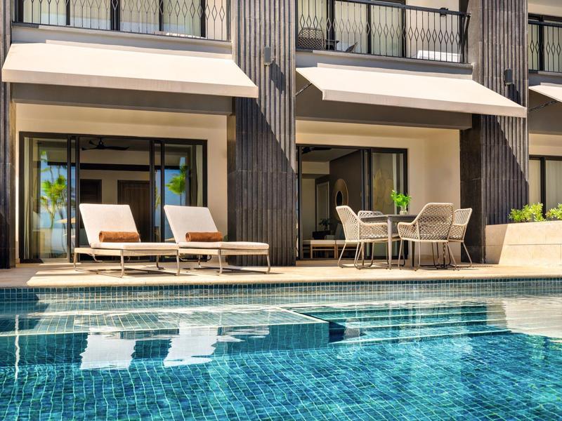 Modernes Hotel mit Pool, Sonnenliegen und Sitzbereich auf der Terrasse.