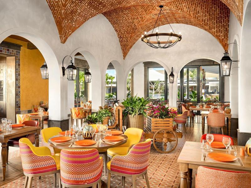 Gemütliches Restaurant mit gemusterten Stühlen, weißen Bögen und Backstein-Gewölbedecke.