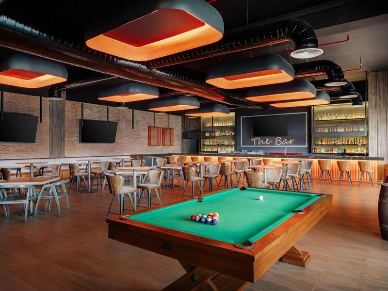 Moderne Bar mit Billardtisch, Hockern und stilvoller Beleuchtung