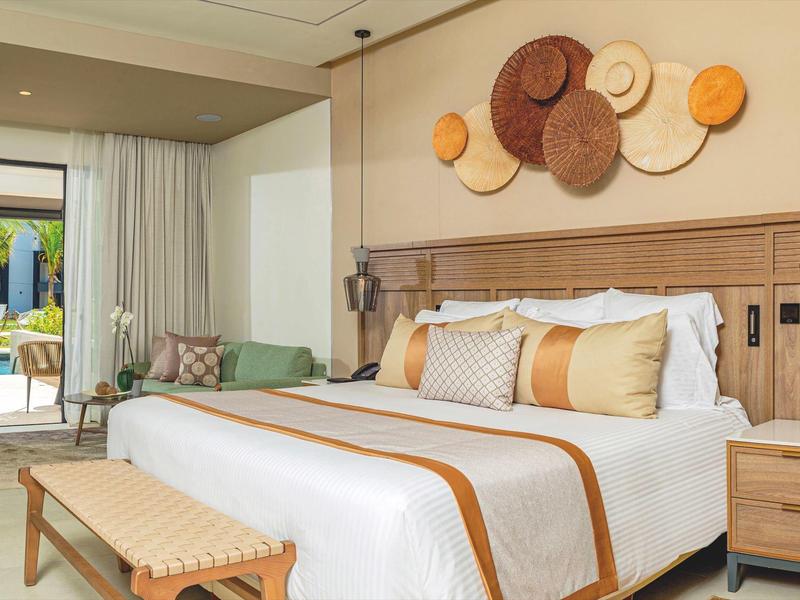 Helles Schlafzimmer mit großem Bett, Holzmöbeln und dekorativen Wandkörben, Zugang zu Terrasse.