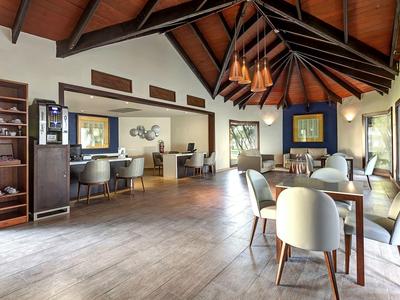 Heller, moderner Hotel-Loungebereich mit Holzdecke, Sesseln und großem Fensterblick.