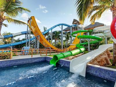 Mehrfarbige Wasserrutschen neben Pool und Palmen in einem tropischen Resort.