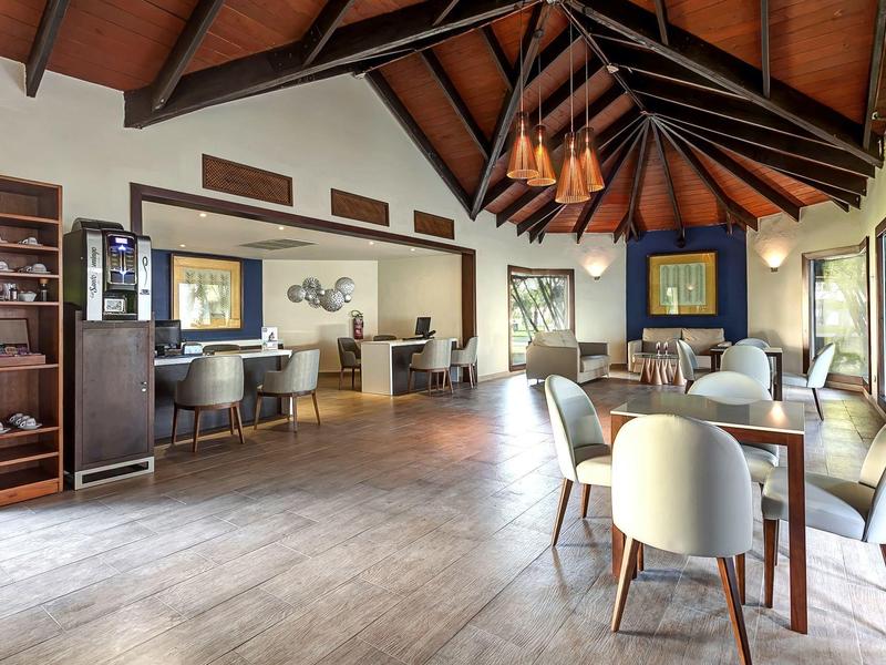 Heller, moderner Hotel-Loungebereich mit Holzdecke, Sesseln und großem Fensterblick.