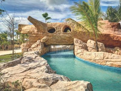 Een resort met een kunstmatige waterloop en rotsachtige omgeving onder een blauwe lucht.