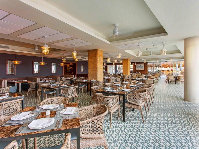 Prostorná moderní jídelna s pletenými židlemi a dekorativní vzorovanou podlahou.