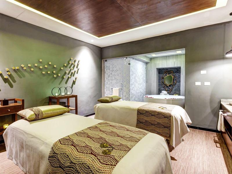 Moderně zařízený hotelový pokoj se dvěma jednolůžky, pracovním stolem a stylovou nástěnnou dekorací.