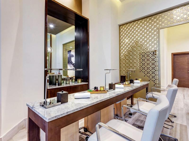 Moderní kadeřnický salon s velkými zrcadly, bílými židlemi a stylovými pracovními místy.