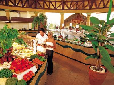 Aerial view of a beach resort with multiple pools, palm trees, and clear turquoise sea.