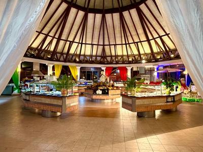 Interior view of a circular market with wooden ceiling and stalls under curtains.