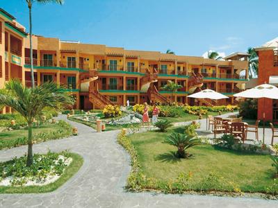 Hotel courtyard with neat garden, seating areas, and orange building in the background