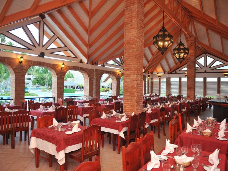 Large open restaurant area with red chairs and set tables in a wooden frame structure.