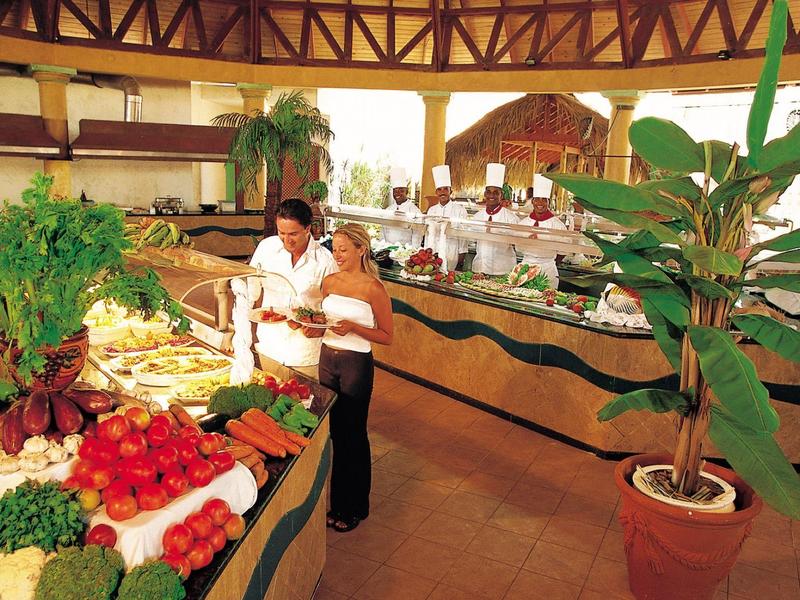Aerial view of a beach resort with multiple pools, palm trees, and clear turquoise sea.