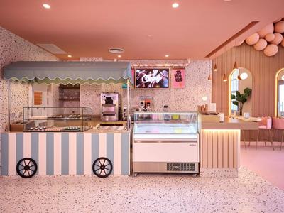Modern café with ice cream display, coffee machine, and pastel-colored interior decor.