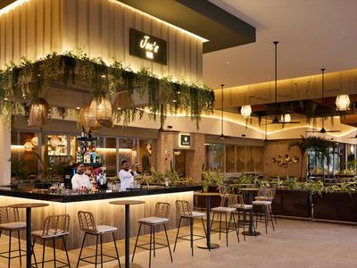 Nowoczesny bar hotelowy z stylowym oświetleniem i roślinnością.