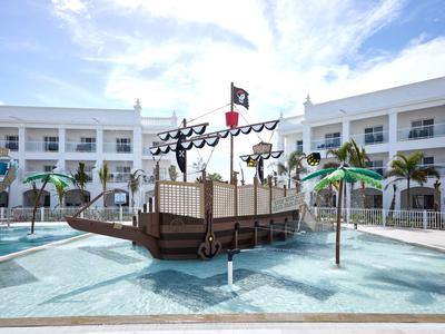Pool with a pirate ship playground surrounded by a hotel building