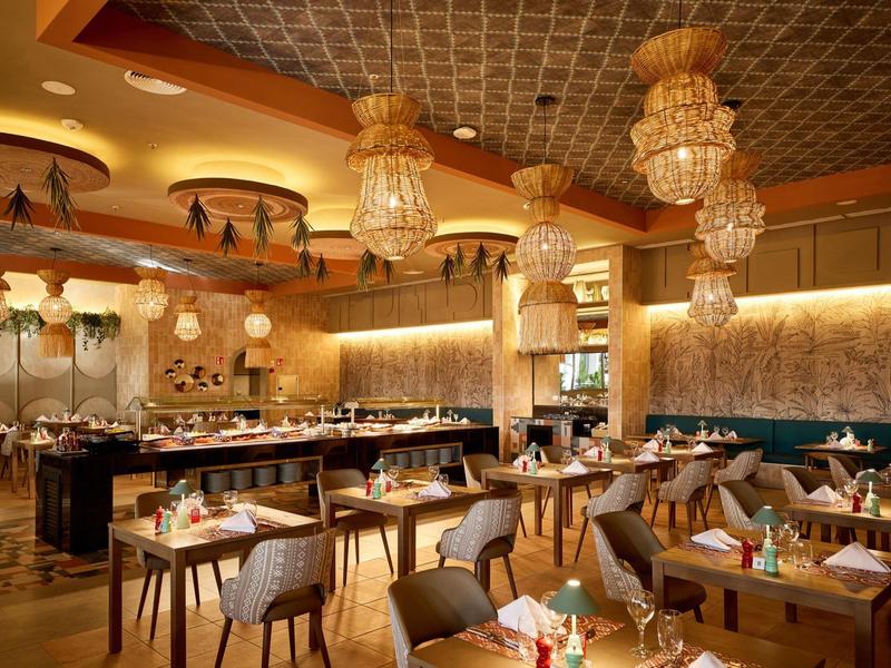 Elegant restaurant with warm lighting, chandeliers, and modern wooden furniture.