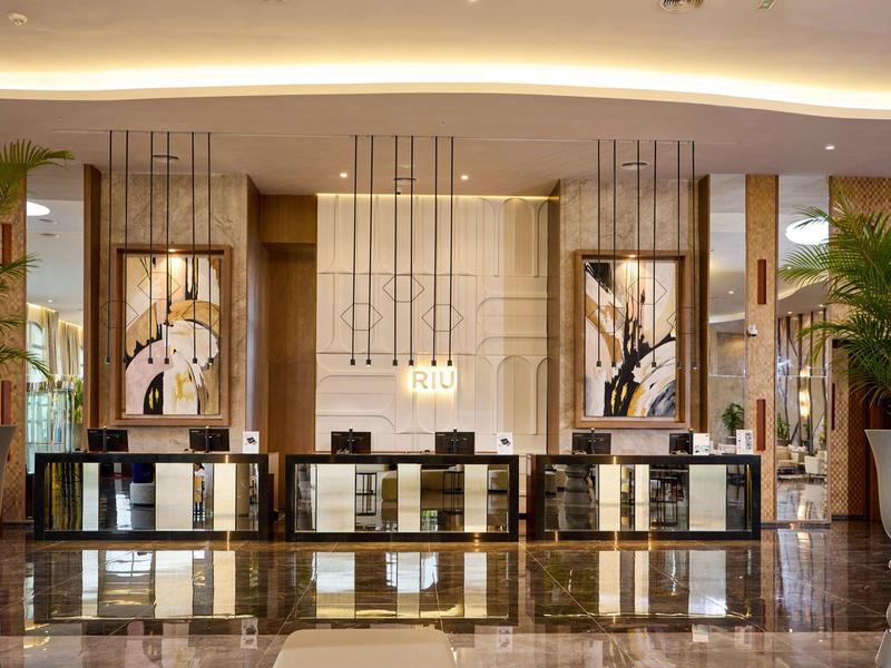 Elegant hotel reception with large front desk and stylish lighting.