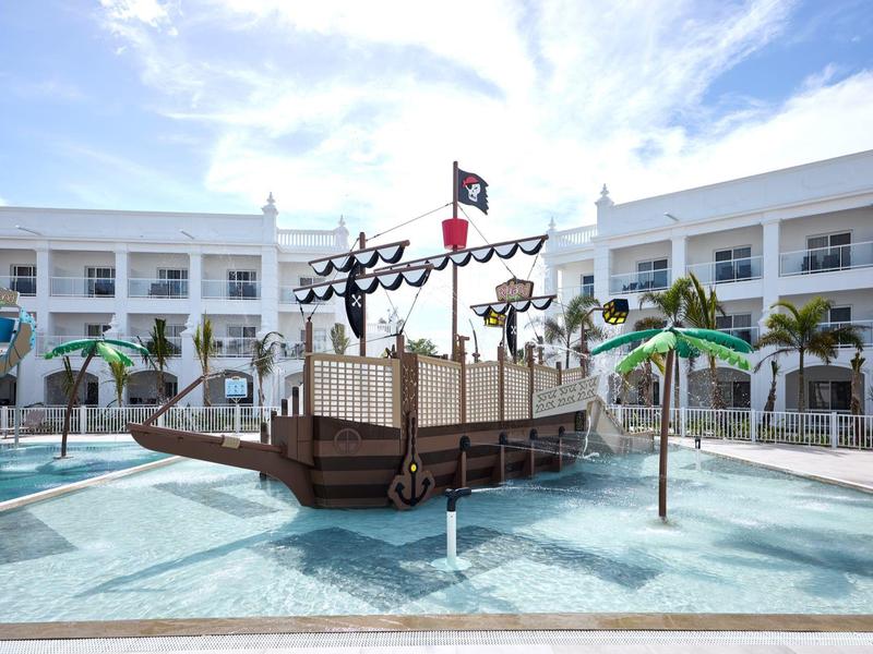Pool with a pirate ship playground surrounded by a hotel building