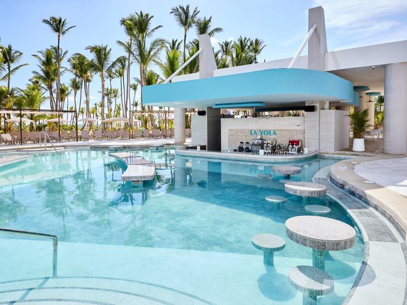 Modern pool with swim-up bar and tropical palm trees in the background.