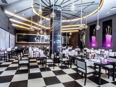 Modern hotel restaurant area with black and white checkered floor and stylish lighting.