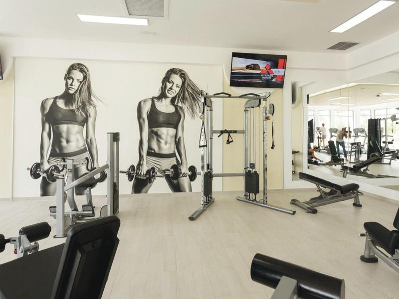 Modern gym with dumbbells, training equipment, and black-and-white wall images of women.