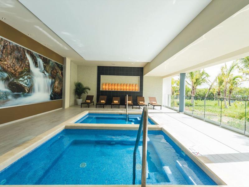 Indoor pool with kids' pool, large windows, and garden view in a modern hotel.