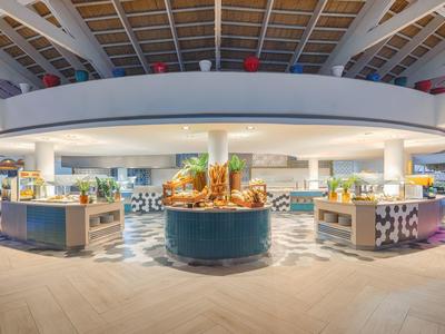 Modern hotel restaurant buffet area with central food island and bright interior.
