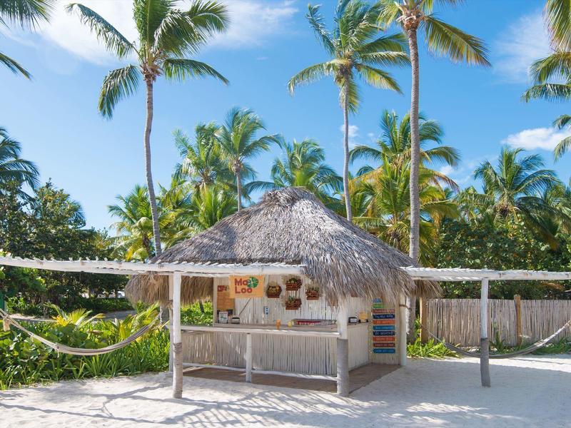 Beach bar with thatched roof and palm trees in the background on a sunny day