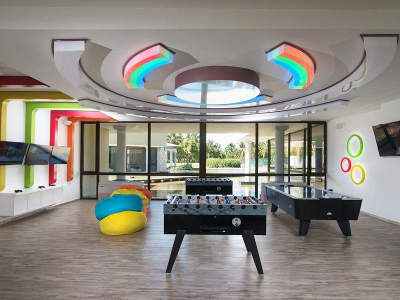 Modern recreation room with foosball, air hockey, bean bags, and colorful LED lights.