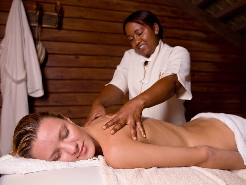 Woman receiving back massage in cozy spa with wooden walls.