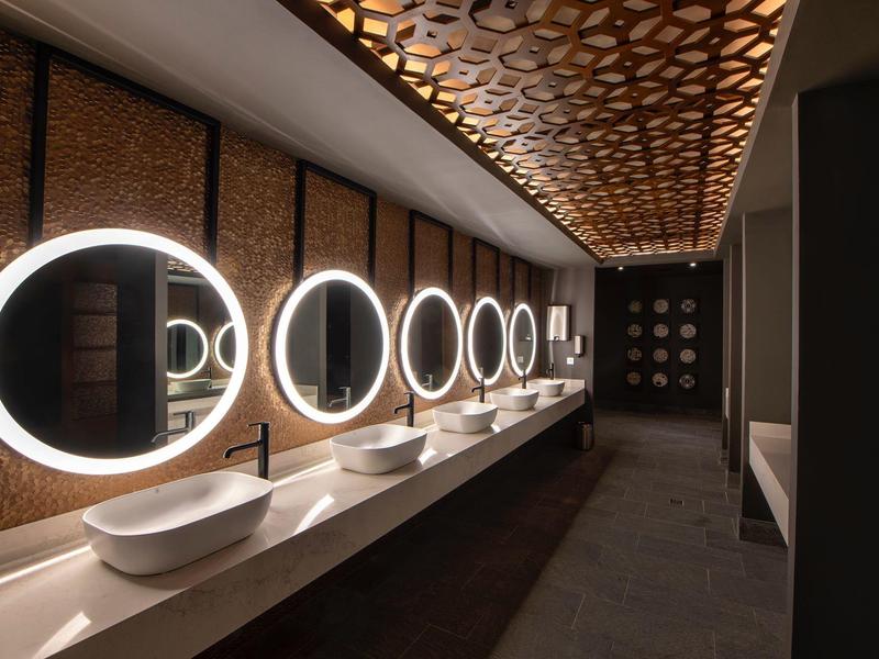 Salle de bain d'hôtel de luxe moderne avec miroirs ronds lumineux et lavabos élégants.