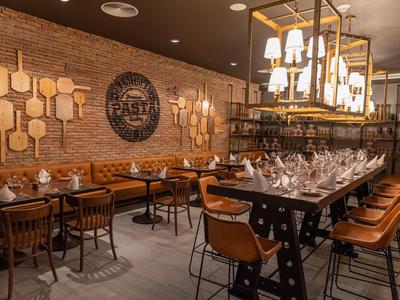 Gemütliches Restaurant mit Ziegelwand, Lederstühlen, Holztischen und rustikaler Beleuchtung.